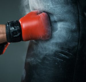 Hand of boxer and punching bag over black background